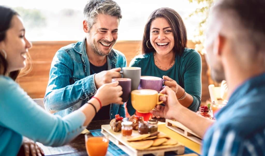 Smiling people clinking coffee cups together