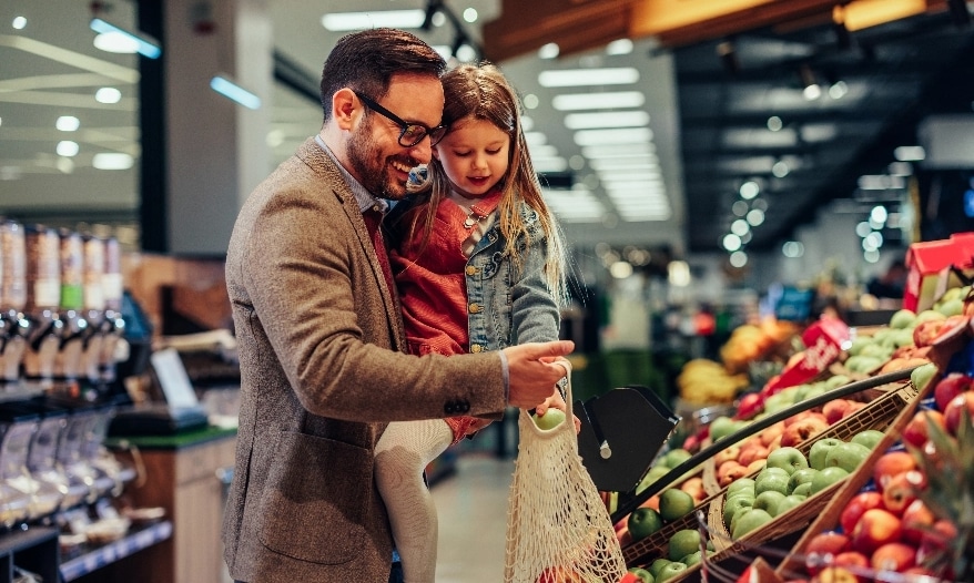 Man in grocery store holding a little girl